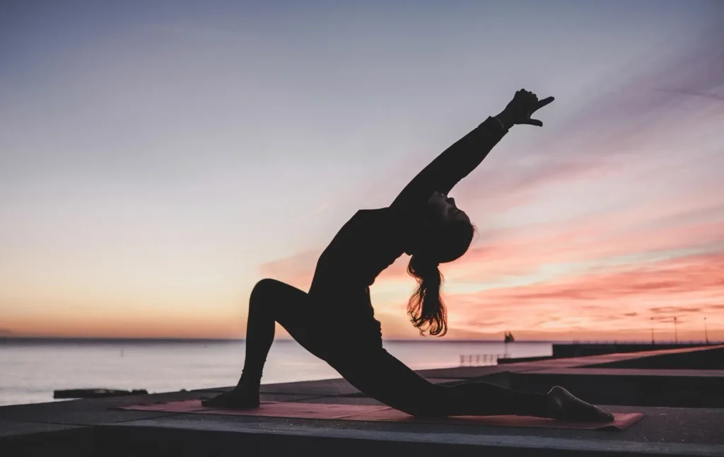 Bóng người tập yoga bên bờ biển lúc hoàng hôn