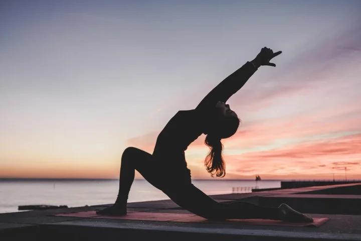 Bóng người tập yoga bên bờ biển lúc hoàng hôn