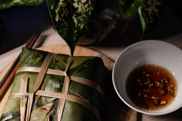 Bánh chưng cắt miếng trên đĩa gỗ kèm nước chấm