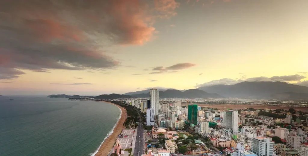 Thành phố biển nhìn từ trên cao với bờ cát dài và dãy núi phía xa