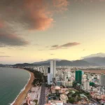 Thành phố biển nhìn từ trên cao với bờ cát dài và dãy núi phía xa