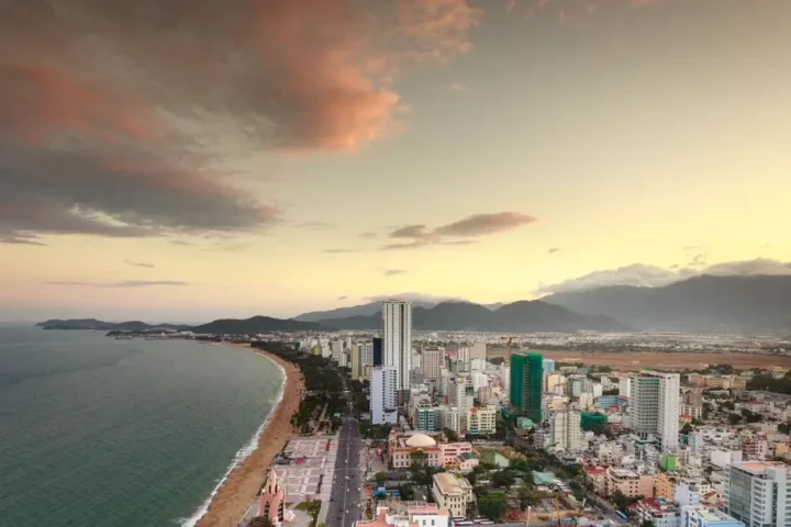 Thành phố biển nhìn từ trên cao với bờ cát dài và dãy núi phía xa