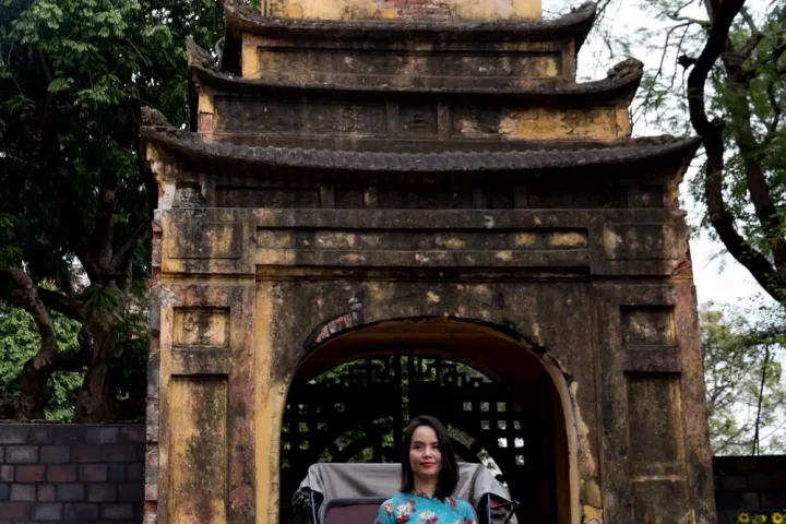 Cổng cổ rêu phong, một người phụ nữ mặc áo dài ngồi phía trong