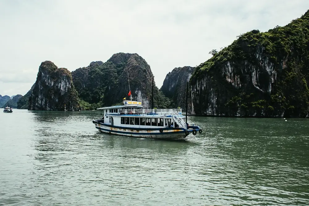 Tàu du lịch đi qua vùng nước xanh giữa các đảo