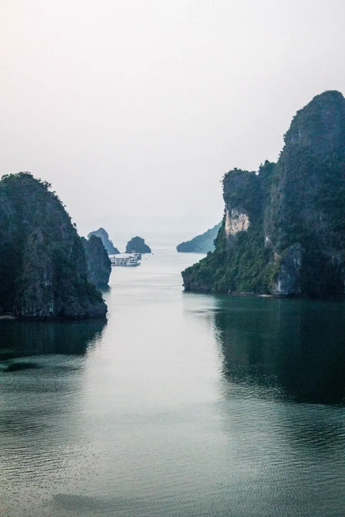 Lạch nước giữa các đảo đá vôi, tàu khách nhỏ phía xa