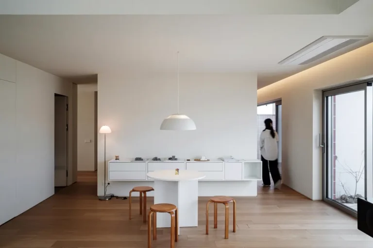Căn phòng trắng tối giản với bàn đảo và ghế gỗ tròn