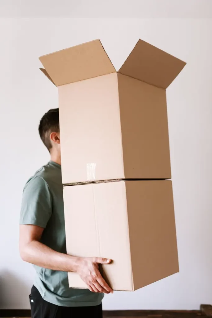 Nhân viên khiêng chồng thùng carton qua phòng