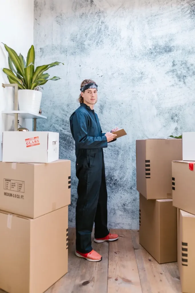 Tổ trưởng cầm bìa kẹp hồ sơ đứng cạnh các thùng carton