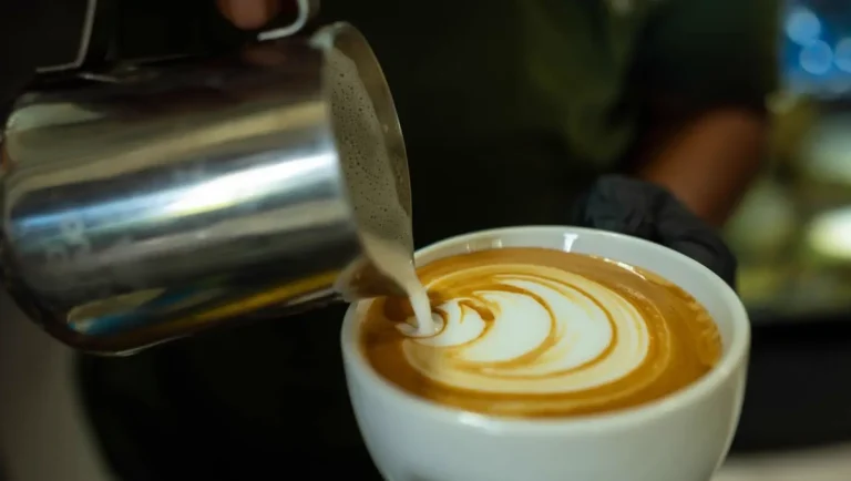 Rót sữa vẽ latte art vào tách cà phê