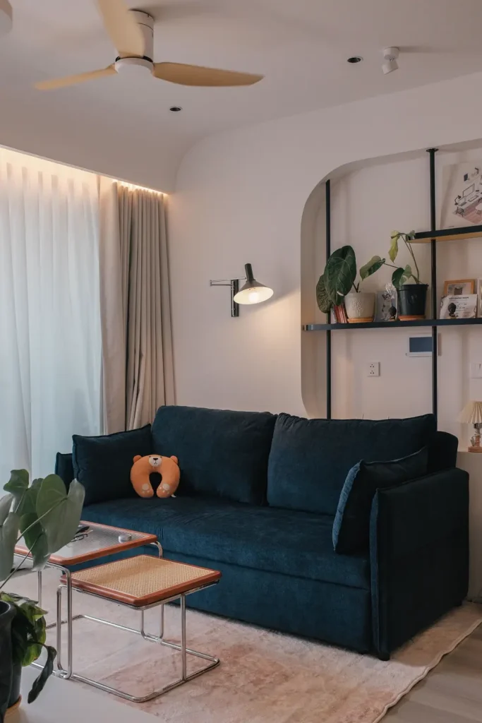 Phòng khách nhỏ với sofa nhung xanh rêu, bàn gỗ thấp và vòm tường