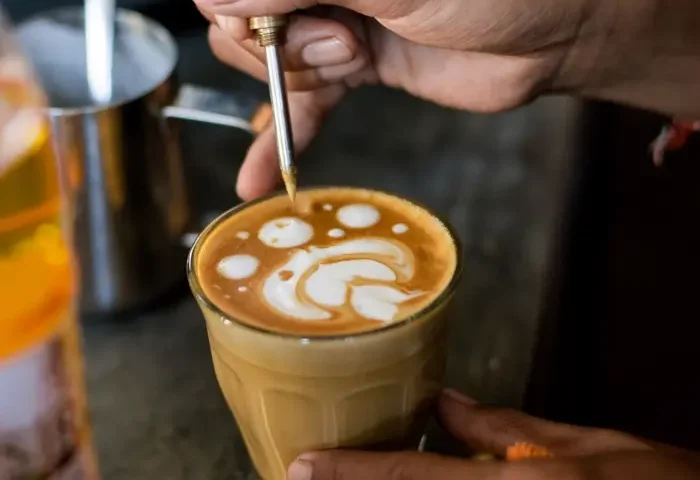 Tay thợ pha vẽ hình trên ly latte