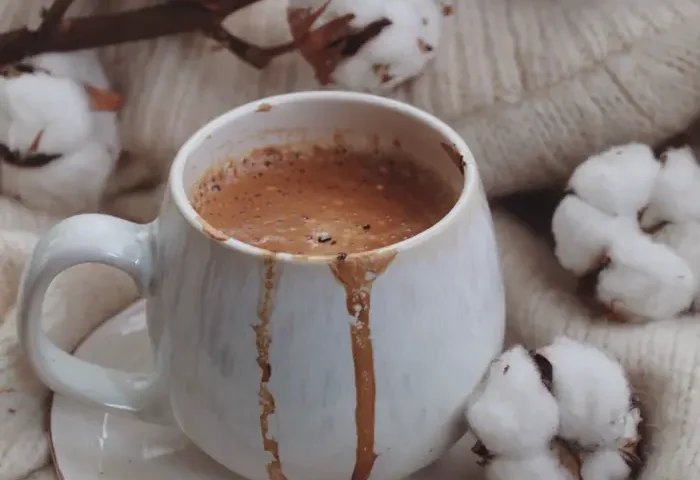 Cốc sô-cô-la nóng tràn bọt bên bông vải