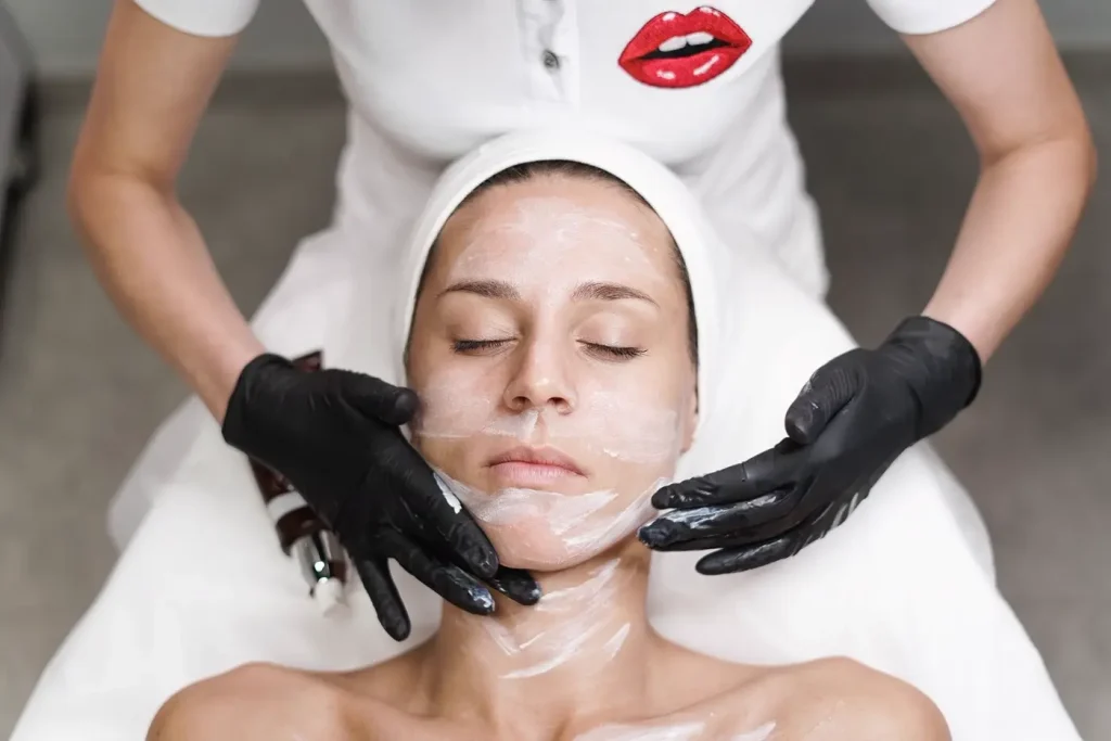 Chuyên viên đeo găng thoa sữa rửa mặt cho khách