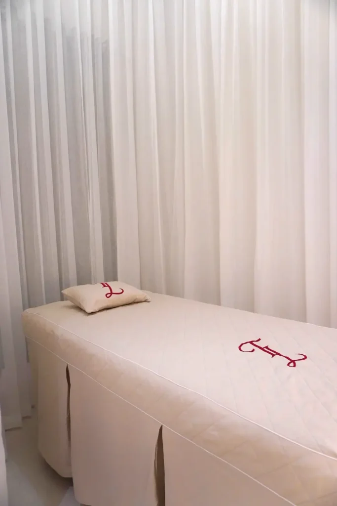 Giường liệu trình trải khăn trắng trong phòng rèm sáng