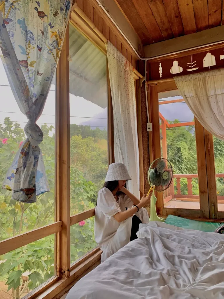 Khách ngồi đọc sách bên cửa sổ gỗ nhìn ra vườn