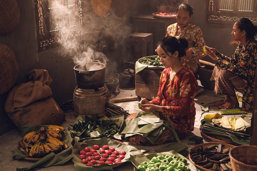 Hai người phụ nữ gói bánh lá bên bếp củi