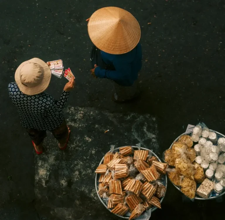 Người bán hàng đội nón lá bên những mẹt bánh nhìn từ trên cao