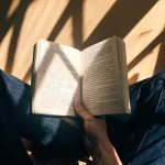 Đôi tay mở một cuốn sách dưới nắng chiều