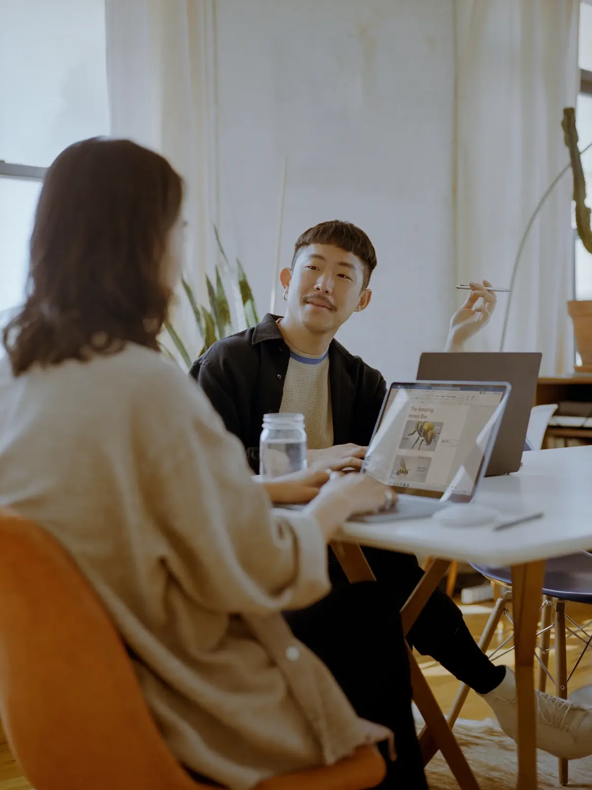 Hai đồng nghiệp trò chuyện bên máy tính xách tay trong văn phòng sáng