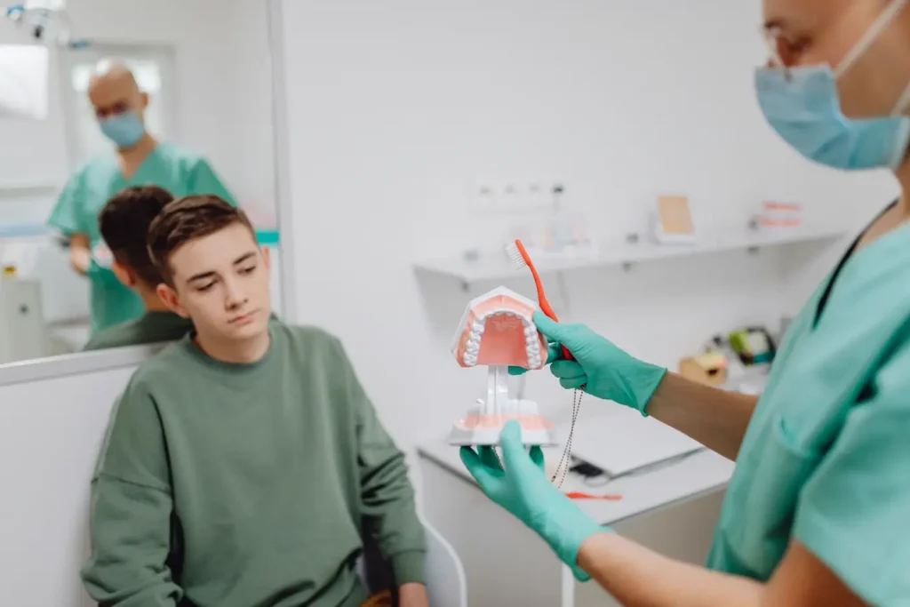 Bác sĩ dạy một cậu bé cách giữ răng sạch bằng mô hình