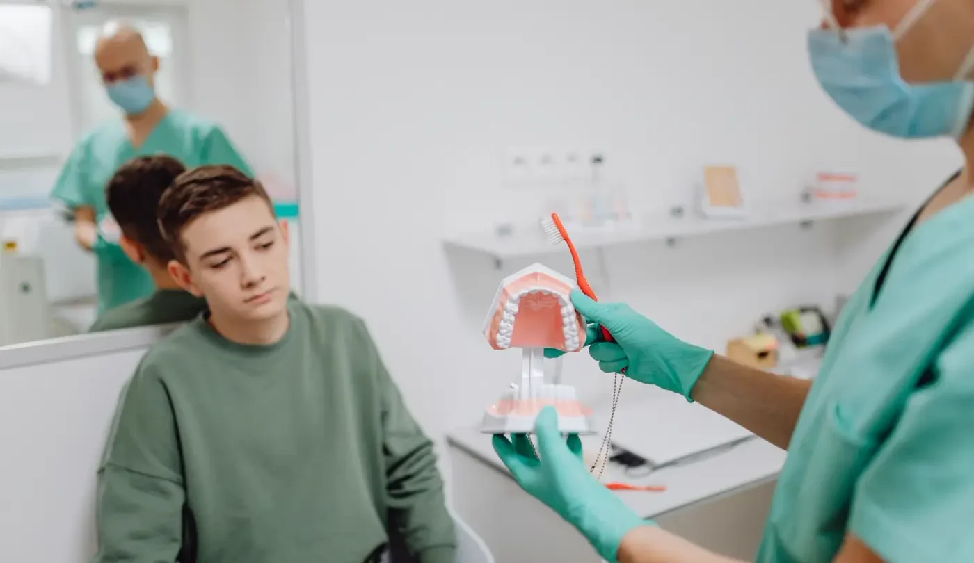 Bác sĩ dạy một cậu bé cách giữ răng sạch bằng mô hình