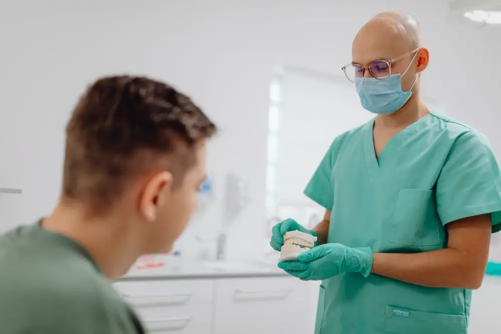 Bác sĩ nam mặc đồ phẫu thuật giải thích cho bệnh nhân