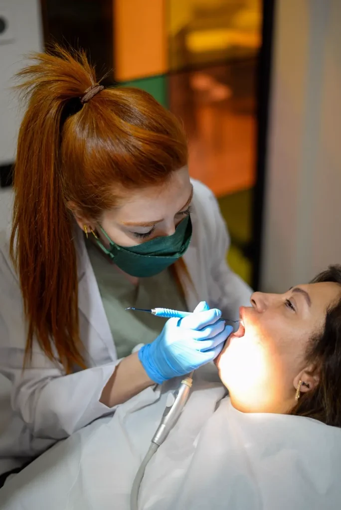 Nữ bác sĩ đeo khẩu trang điều trị răng dưới đèn sáng