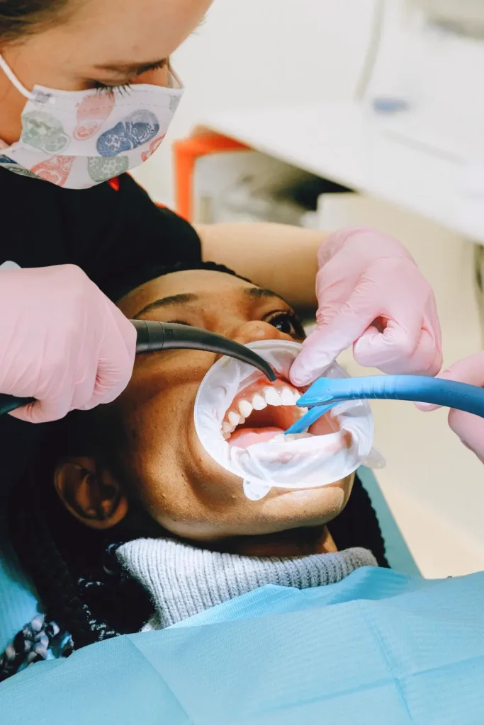 Bác sĩ làm sạch răng cho bệnh nhân bằng dụng cụ hút nước