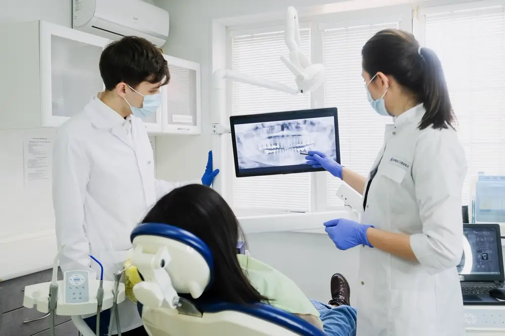 Bác sĩ chỉ phim chụp răng 3D trên màn hình cho bệnh nhân