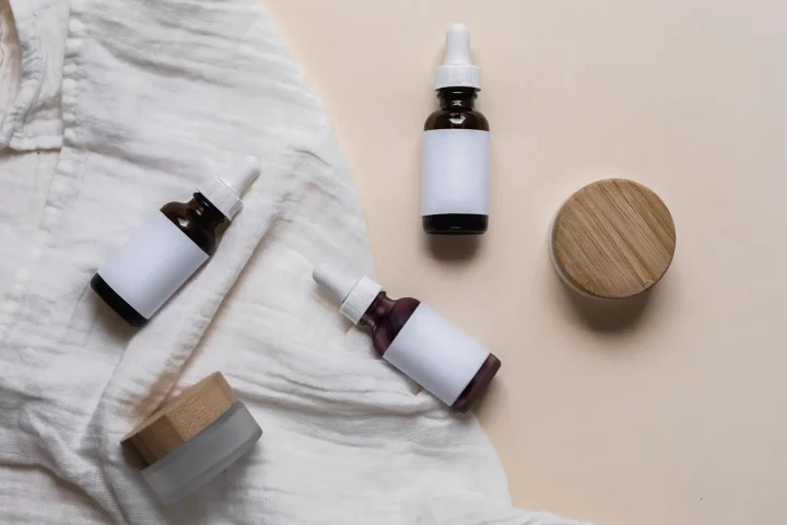 Các lọ tinh chất nhãn trắng và hũ nắp gỗ trên khăn linen