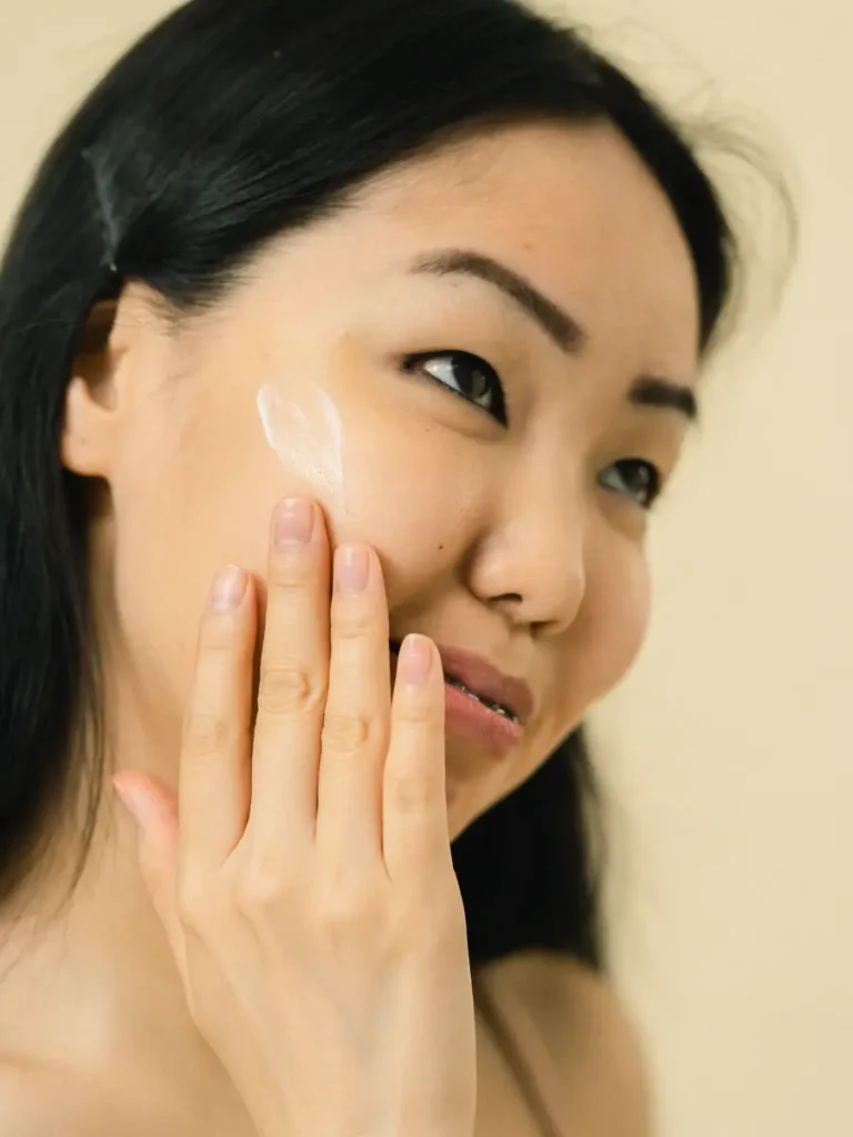 Cô gái chấm một chút kem trắng lên gò má, nền be ấm