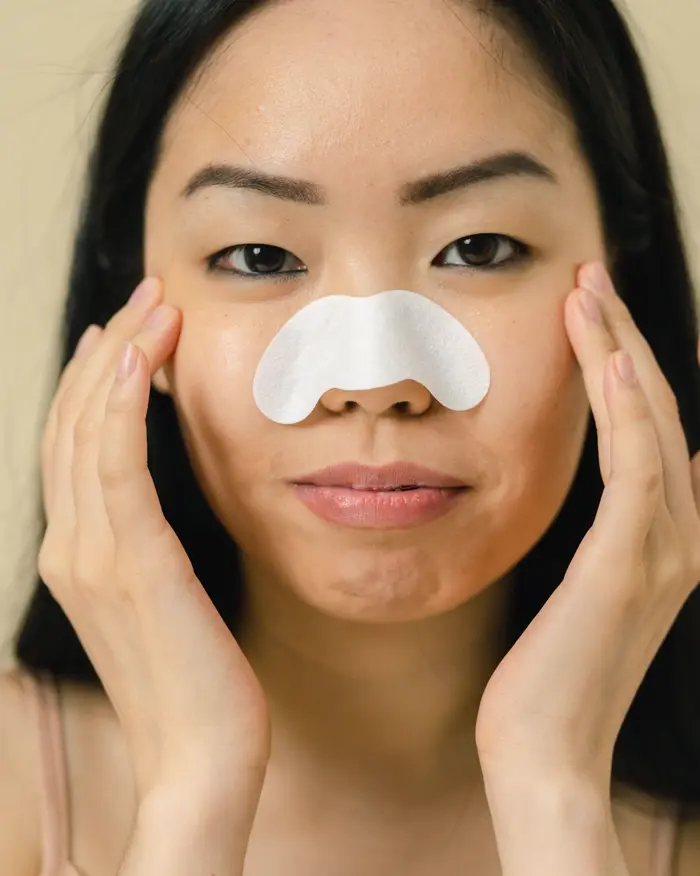 Cô gái dán miếng lột mụn mũi, hai tay ôm má